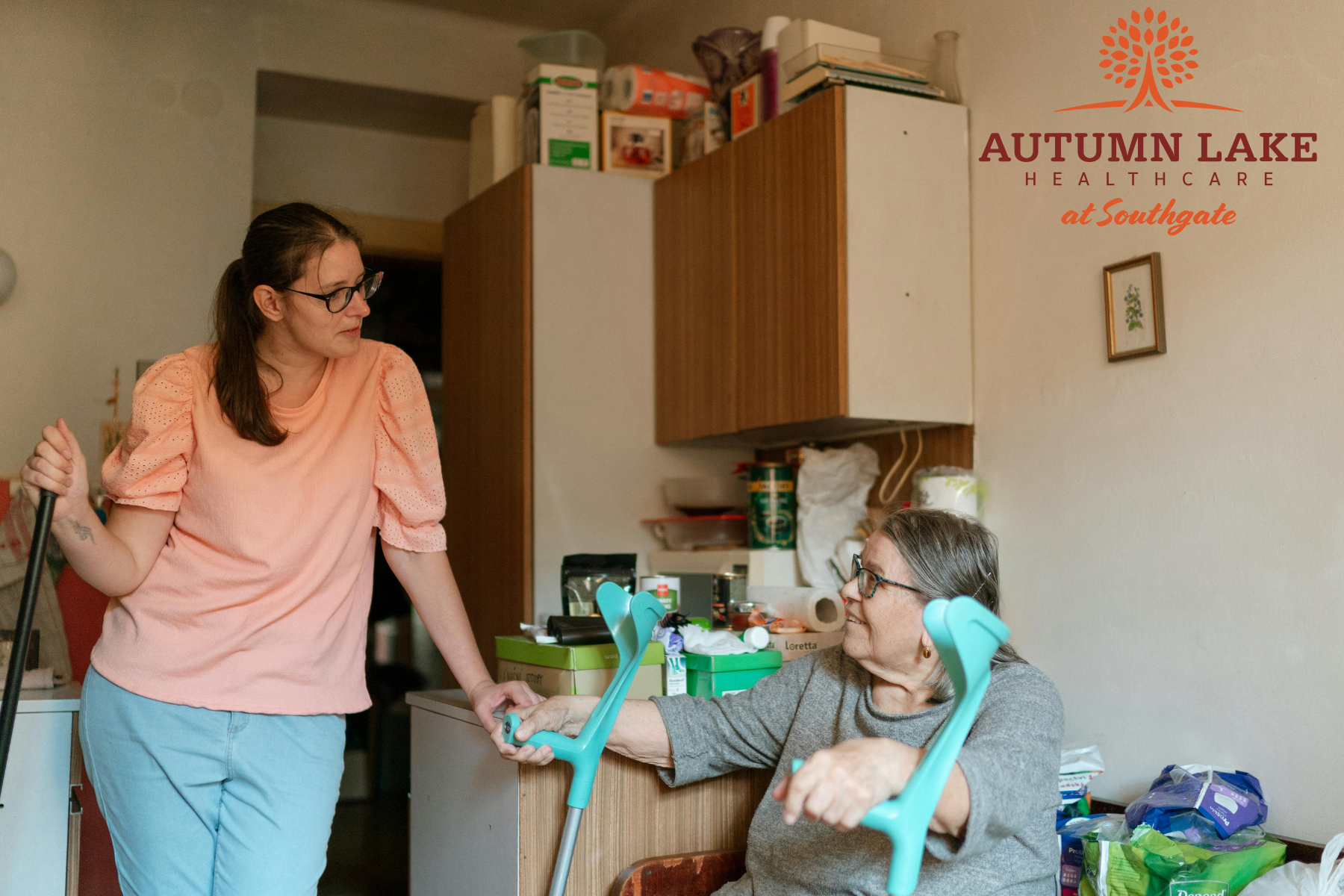 Caregiver assisting a senior woman using forearm crutches in a senior living